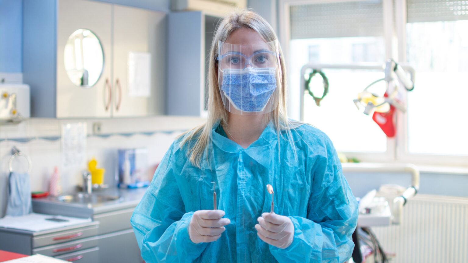 Female dentist in a protective suit with a protective shield and mask