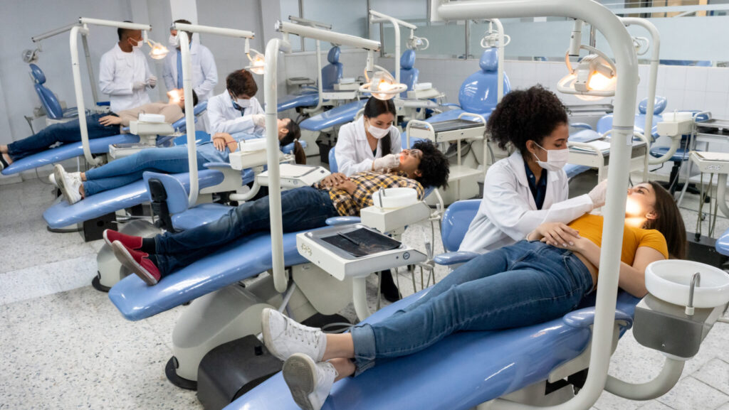 Students at dental school examining the teeth of some patients - education concepts