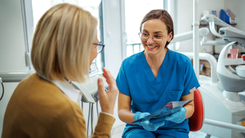 Nurse talking with senior female patient at dentist's office