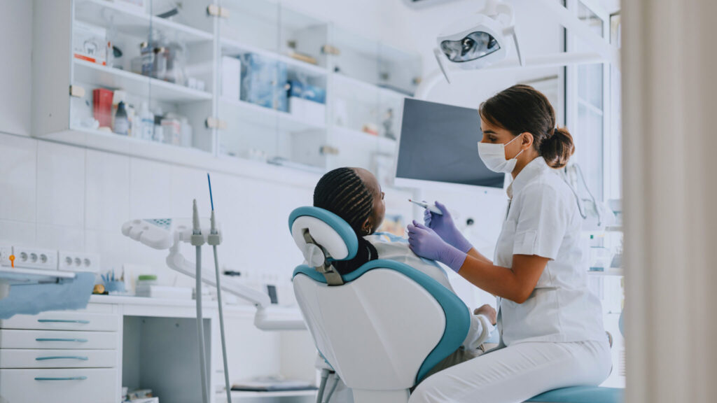 Dentist examining a patient in a modern dental clinic. Professional dental care and hygiene practice.