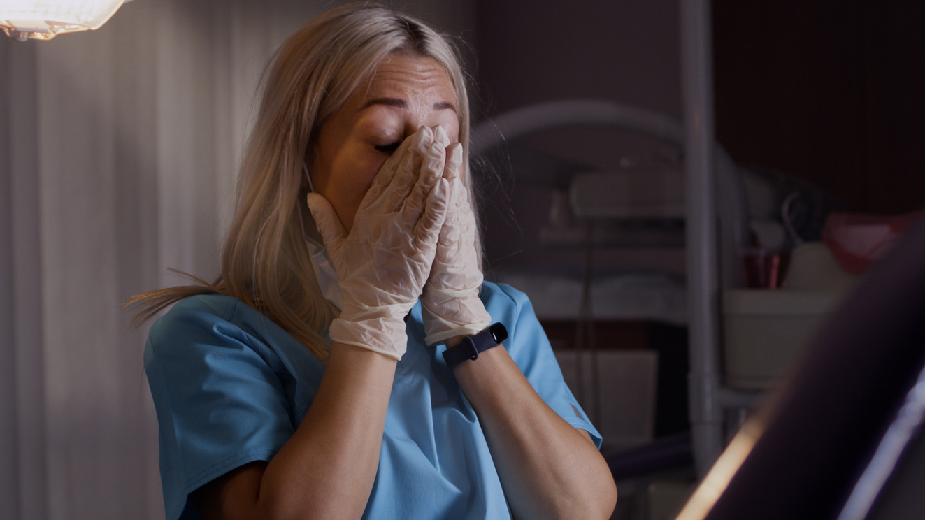 Exhausted dental specialist taking off protective shield and mask rubbing face after long work day